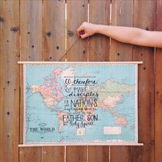 a map hanging on the side of a wooden fence with a person's hand holding it