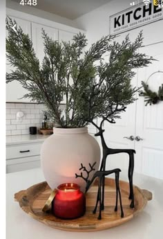 a white vase sitting on top of a table next to a red candle and some deer figurines