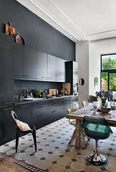 a dining room table and chairs in front of an open kitchen with lots of windows