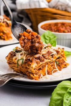 a plate with lasagna on it being lifted by a fork