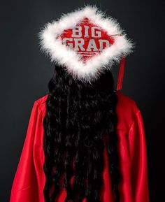 a man with long black hair wearing a red graduation gown and white feathered hat