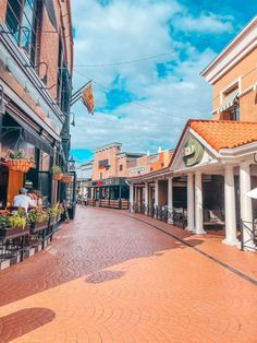 an empty street with tables and chairs on the side walk in front of buildings that are brick