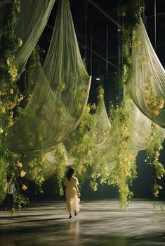 a woman is standing in the middle of a room with sheer curtains hanging from it's ceiling