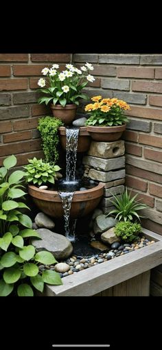 a water fountain surrounded by plants and rocks in front of a brick wall with text overlay