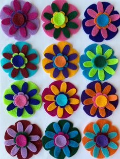 several different colored felt flowers on a white surface