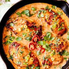 a skillet filled with chicken covered in sauce and garnished with fresh herbs