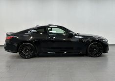 a black sports car is parked in a large room with tile flooring and white walls