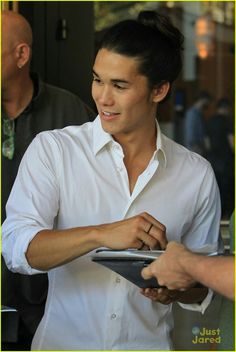 a man in a white shirt is holding a clipboard and looking at another person