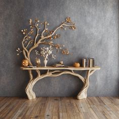 a wooden table topped with books and vases next to a tree branch wall mural