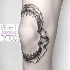 a black and white photo of a shark's teeth on the side of a woman's leg