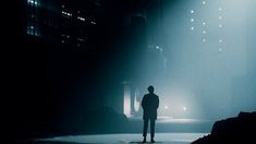 a man standing in the middle of a dark room with light coming from behind him