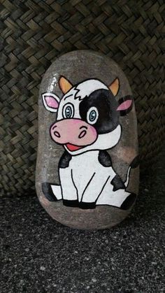 a painted cow sitting on top of a rock