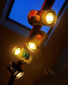 three beer bottles are hanging from the ceiling in front of a window with lights on it