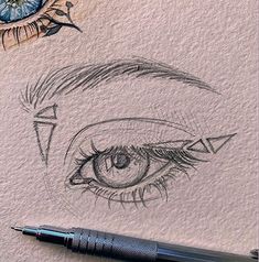 an eye drawn on paper with a pen next to it and another drawing in the background