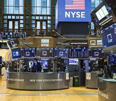 the new york stock exchange building is full of electronic monitors and screens, with people working at their desks