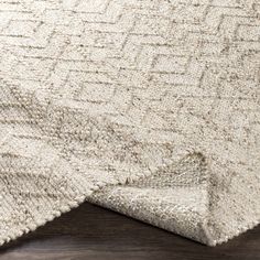 a close up view of the corner of a rug with a wooden floor in the background