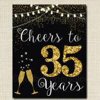 cheers to 35 years sign with gold glitter and champagne glasses on black, against a white background