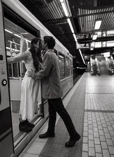 a man and woman standing on the side of a subway train as it pulls into a station