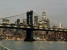 the city skyline is lit up at night as seen from across the water in new york