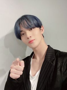 a man with blue hair wearing a black suit and white t - shirt is posing for the camera