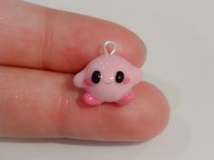 a small pink toy with black eyes on it's face sitting in someones hand