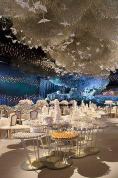 a banquet hall with many tables and chairs covered in paper cranes hanging from the ceiling