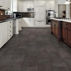 a large kitchen with white cabinets and black counter tops, along with dark wood flooring