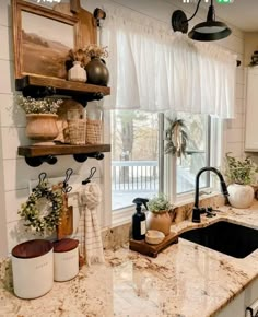 a kitchen with white cabinets and marble counter tops, an open window over the sink