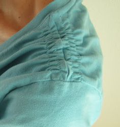 a woman wearing a blue shirt with her hand on her hip and the back of her shoulder