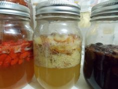 three jars filled with different types of liquid and food in them on top of a table