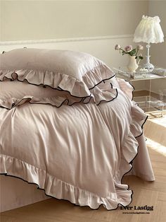 a bed with two ruffled pillows and a pink comforter