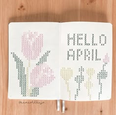 an open book with cross stitch flowers on it and the words hello april written in small letters