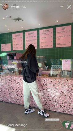 a woman standing in front of a pink counter