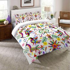 a bed with colorful comforters and pillows in a room