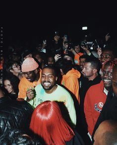 a group of people standing around each other in front of a man with red hair