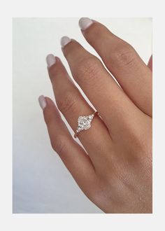 a woman's hand with a diamond ring on top of her finger and the other hand holding an engagement ring