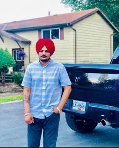 a man in a turban standing next to his truck