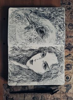 a drawing of two faces on top of a piece of paper next to a pen