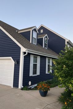 a blue house with white trim and two garage doors on the front door is shown