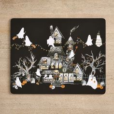 a halloween themed placemat with ghost houses and pumpkins in the yard on it