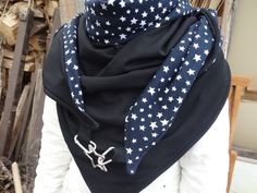 a woman wearing a black scarf with white stars on it and a blue bandanna around her neck