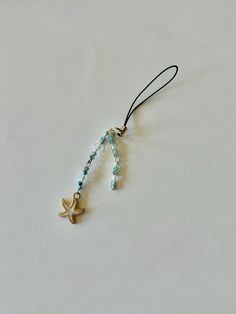 a starfish charm is hanging from a cord on a white surface with blue beads