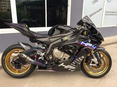 a motorcycle parked in front of a building with gold rims on it's tires