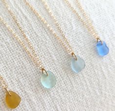 four different colored glass hearts on gold chains