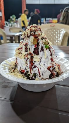 a bowl filled with ice cream and toppings on top of a wooden table in a restaurant