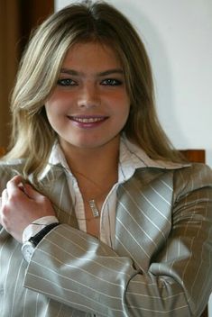 a woman in a suit posing for the camera with her hands on her chest and arms crossed