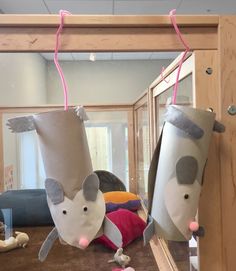 two stuffed animals hanging from the ceiling in front of a mirror with pink string attached to it