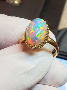 Natural crystal opal, galaxypattern, 10x14mm 5.75cts bright with purple background, rainbow slashes of fiery colors mounted on a 14k solid gold gallery style bezel ring . Handmade Oval Opal Ring Fine Jewelry, Handmade Oval Opal Ring In Fine Jewelry Style, Oval Opal Gemstone Rings, Yellow Gold Ethiopian Opal Ring In Oval Shape, Hallmarked Oval Opal Ring, Handmade Oval Opal Ring In Yellow Gold, Hallmarked Oval Ethiopian Opal Rings, Yellow Gold Opal Ring With Cabochon, Oval Pink Opal Gemstone Rings