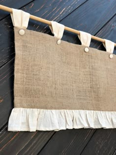 a piece of burlock hanging from a clothes line on a wooden floor with white ruffles