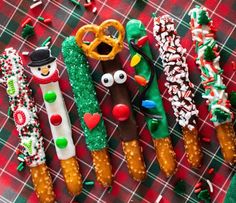 christmas treats made to look like characters are lined up on a plaid tablecloth with candy canes and pretzels